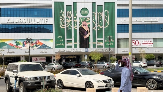 A Saudi man walks past a banner of Saudi Crown Prince Mohammed bin Salman displayed on a commercial building in Riyadh, Saudi Arabia, October 15, 2026. Picture taken with a mobile phone.
