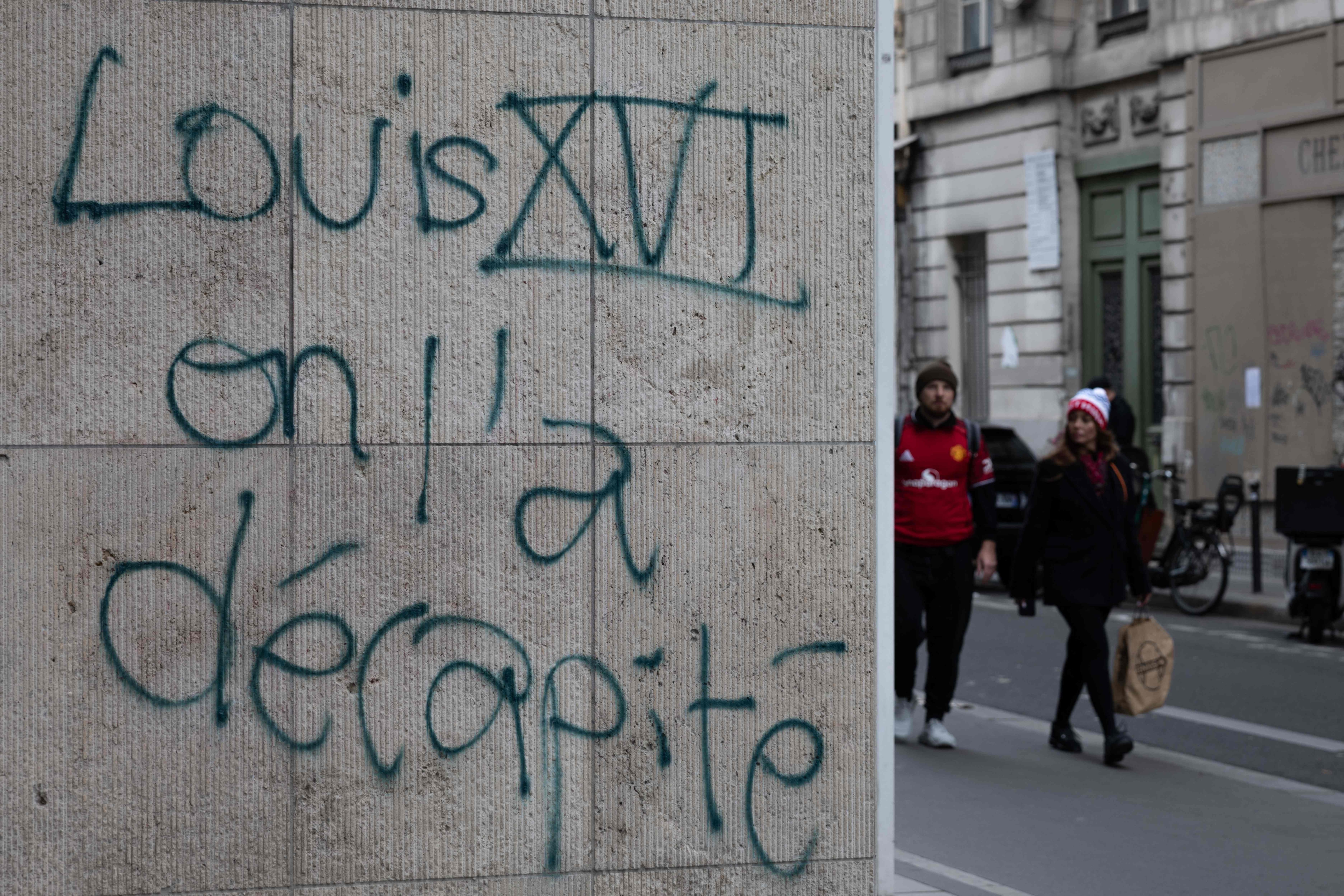A couple walks past graffiti reading "Louis XVI, we beheaded him" in central Paris. (AFP Photo) A couple walks past graffiti reading "Louis XVI, we beheaded him" in central Paris. (AFP Photo)