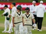 Australia's Scott Boland, center left, and teammate Travis Head, center right, leave the field at the end of day's play on day four of the second cricket test match between South Africa and Australia