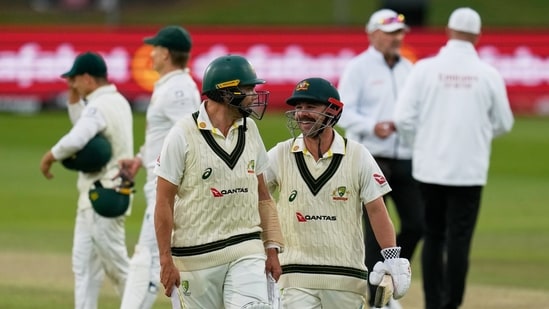 Australia's Scott Boland, center left, and teammate Travis Head, center right, leave the field at the end of day's play on day four of the second cricket test match between South Africa and Australia