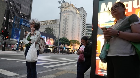 People use mobile phones as they wait for public transportation, as smartphone theft has become part of Brazil's electoral debate, in Sao Paulo, Brazil.