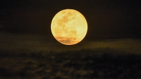 A full moon rises above Singapore on November 16, 2024. (Photo by Roslan RAHMAN / AFP)