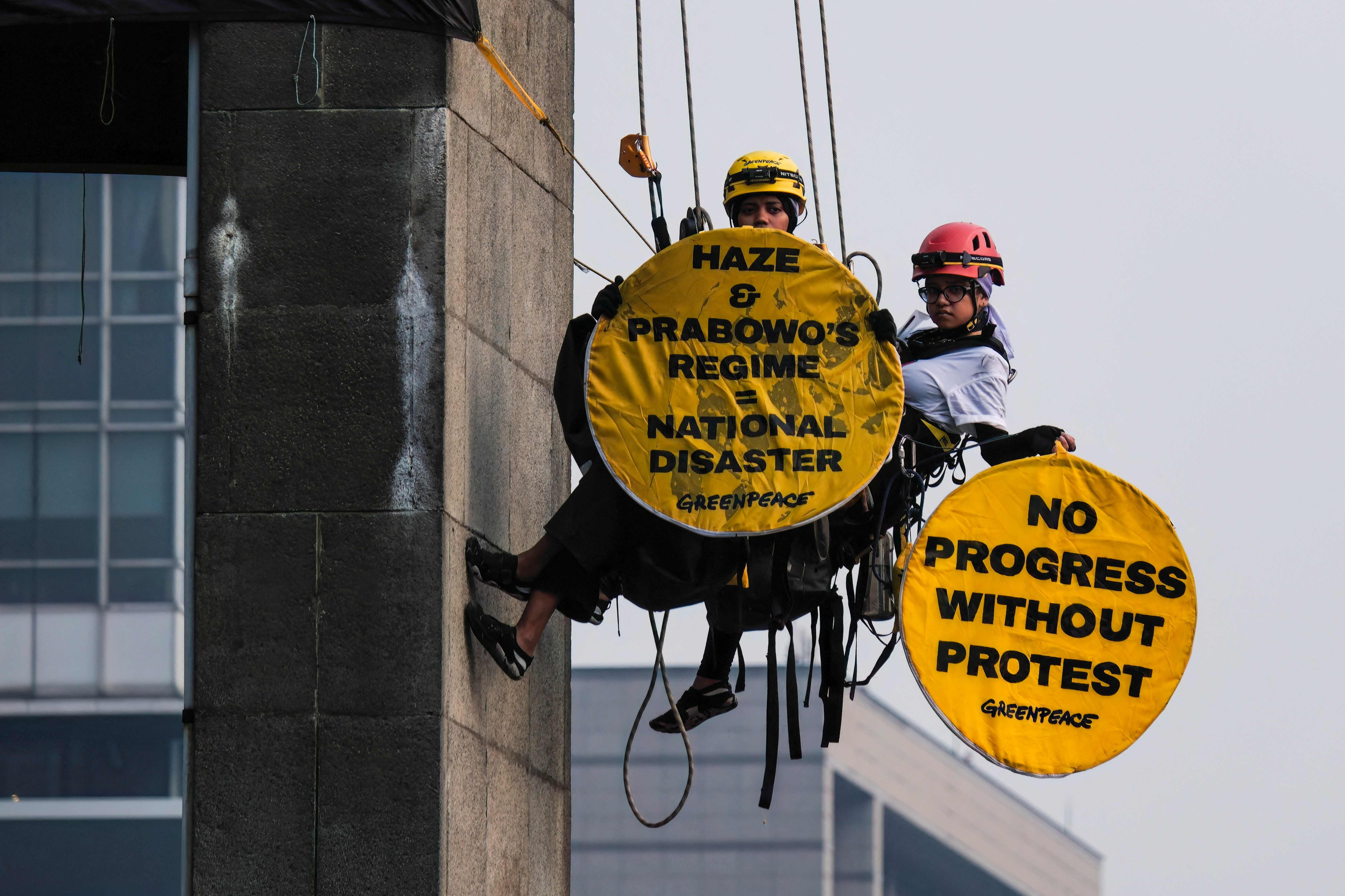 Greenpeace Indonesia activists hanging from the Welcome Statue at the Hotel Indonesia Roundabout hold protest signs in Jakarta on October 20, 2026. (AFP) Greenpeace Indonesia activists hanging from the Welcome Statue at the Hotel Indonesia Roundabout hold protest signs in Jakarta on October 20, 2026. (AFP)