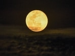 A full moon rises above Singapore on November 16, 2024. (Photo by Roslan RAHMAN / AFP)