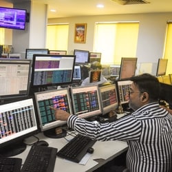 Share brokers track market movements on their computer screens at a trading office, in Kolkata.