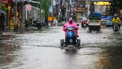 A commuter wearing a raincoat wades through waterlogged General Patters Road amid heavy rainfall, in Chennai on Wednesday. (ANI Photo) (Esha A) A commuter wearing a raincoat wades through waterlogged General Patters Road amid heavy rainfall, in Chennai on Wednesday. (ANI Photo) (Esha A)