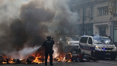 A French police officer extinguishes burning bicycles during a demonstration against the cost of living and rising fuel prices in Paris as part of nationwide protests. (REUTERS)