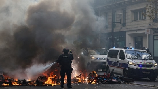 A French police officer extinguishes burning bicycles during a demonstration against the cost of living and rising fuel prices in Paris as part of nationwide protests.(REUTERS)