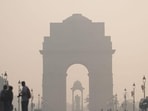 A layer of smog engulfs the surrounding at India Gate as people walk along amid poor air quality. (PTI photo)