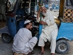 Shehzad Bhai, 45, an auto electrician, repairs a magnet coil as a rickshaw driver waits for passengers, amid rising fuel and liquefied petroleum gas (LPG) prices.(REUTERS)
