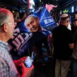 A supporter of Israeli Prime Minister Benjamin Netanyahu, leader of the Likud party, displays a flag depicting him at Mahane Yehuda market, ahead of Israel's national election, in Jerusalem. 