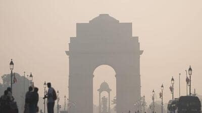 A layer of smog engulfs the surrounding at India Gate as people walk along amid poor air quality. (PTI photo)