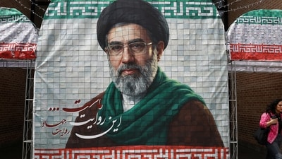 A woman walks next to a banner with a picture of Iran's new Supreme Leader Mojtaba Khamenei in Tehran, Iran. (via REUTERS)