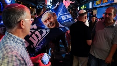 A supporter of Israeli Prime Minister Benjamin Netanyahu, leader of the Likud party, displays a flag depicting him at Mahane Yehuda market, ahead of Israel's national election, in Jerusalem. (REUTERS)