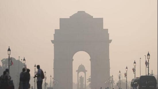 A layer of smog engulfs the surrounding at India Gate as people walk along amid poor air quality. (PTI photo)