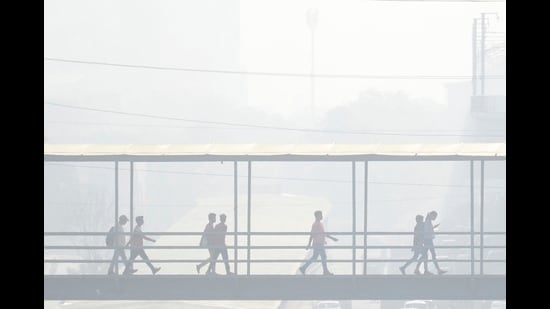 Gurugram: Commuters use a foot overbridge amid smog, in Gurugram. (PTI)