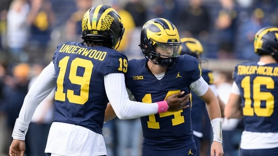 Michigan quarterback's Bryce Underwood (19) and Tommy Carr (14) exchange pleasantries during pregame warmups before their NCAA college football game against Indiana in Ann Arbor, Michigan.