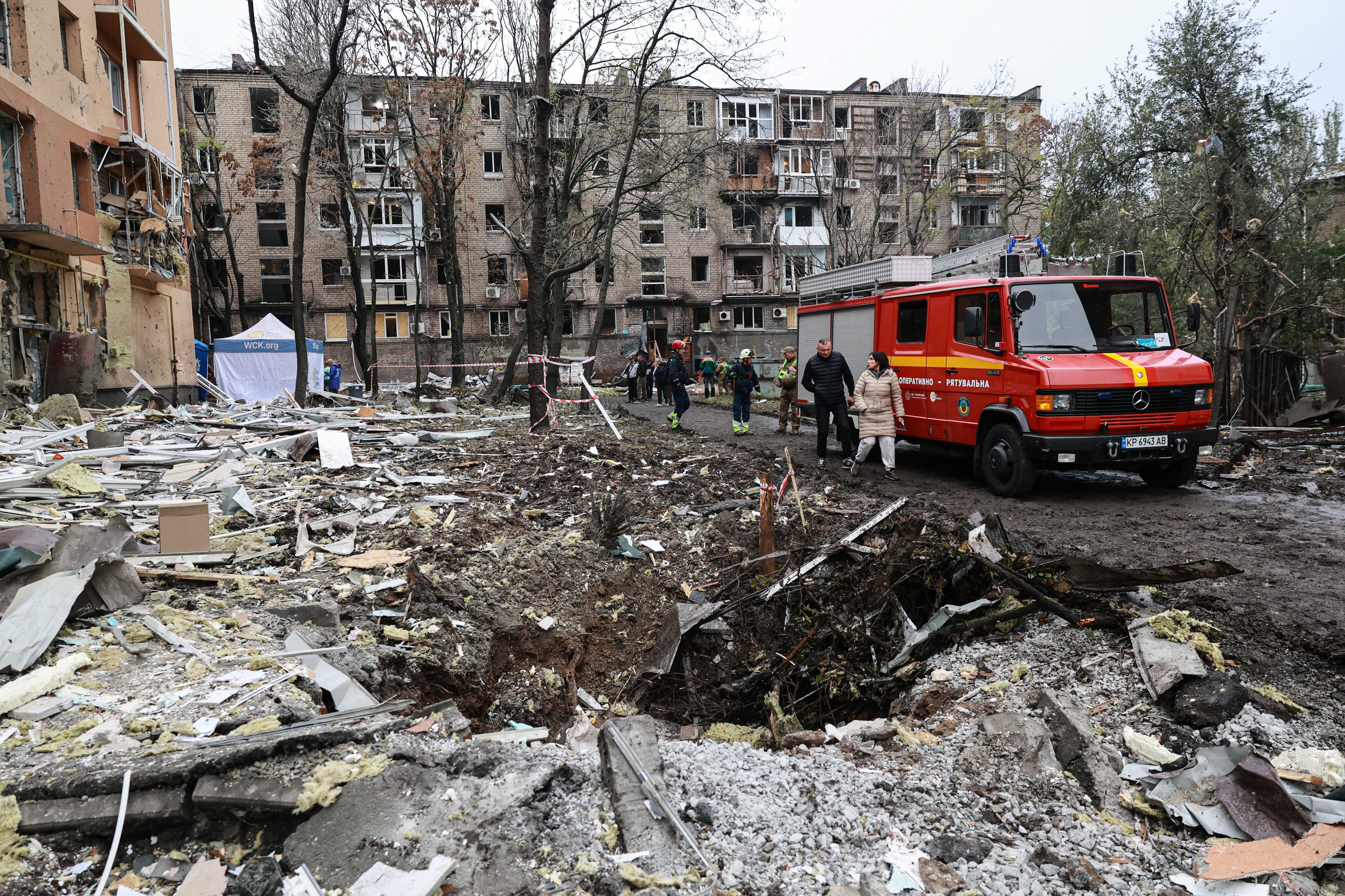 People walk past a crater in front of a residential building damaged by a Russian airstrike in Zaporizhzhia, Ukraine. (AP Photo)