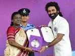 President Droupadi Murmu honours actor Dhanush with a Special Mention (Actor) for the film 'Captain Miller' at the 72nd National Film Awards ceremony, in Kevadia. 