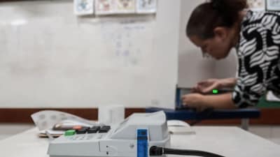 A woman looks at the printed results from a ballot box at a polling station in Jacarepagua, in the southern zone of Rio de Janeiro, Brazil, during the presidential runoff election on October 25. (AFP)