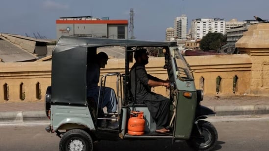 A motorised auto-rickshaw powered by liquefied petroleum gas (LPG) passes a bridge amid rising fuel and LPG prices due to the Iran conflict, in Karachi, Pakistan. (Reuters)