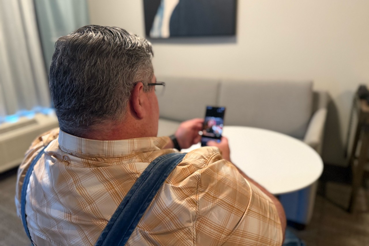 Garrick Stafford looking at a photo of 'Sarah' on his phone.