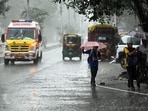 An ambulance and pedestrians holding umbrellas wade through a rain-slicked road amid heavy rainfall triggered by Cyclone Arnab, in Patna on Saturday.