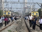Commuters walk on railway tracks as a central railway line gets stuck due to a signal failure, in Mumbai on Monday.
(ANI)