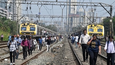 Commuters walk on railway tracks as a central railway line gets stuck due to a signal failure, in Mumbai on Monday. (ANI)