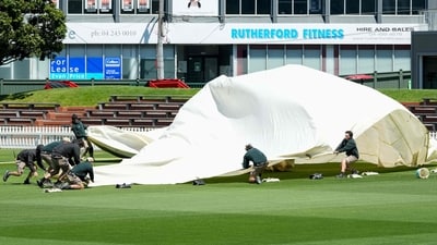 Ground staff struggle with the covers amid very strong winds during a training session at the Basin Reserve in Wellington. (AFP)