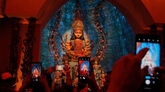 People take photos of an idol of Hindu goddess Durga at a makeshift worship venue on the last day of the festival Durga Puja.
