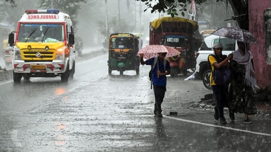 Pedestrians holding umbrellas amid heavy rainfall triggered by Cyclone Arnab in Patna on Saturday.
