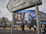 People walk past a Likud party campaign billboard featuring Israeli Prime Minister Benjamin Netanyahu alongside opposition party leaders and bearing the Hebrew slogan 