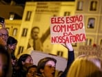 A woman holds a sign reading "They are afraid of our strength" during a protest against the housing shortage, soaring rents and low wages in front of the Portuguese Parliament in Lisbon.