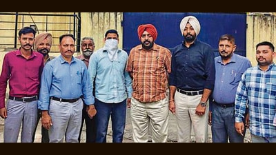 The accused (with his face covered) in the custody of VB officials in Ludhiana on Wednesday. (HT Photo)