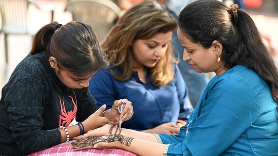 Gram it: Karwa Chauth vibes have taken over the city today as women have been seen shopping for festive bangles and jewellery. Here's a shopper who paused to get mehendi applied on her hands, near Hanuman Temple in Connaught Place, on Tuesday.(Photo: Sonu Mehta/Hindustan Times)