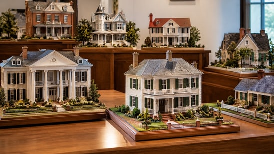 Representative image showing a collection of handcrafted miniature houses displayed in a museum-style gallery.