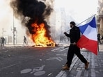 A protester holds a French flag next to burning objects amid clashes in a street near the Place de Republique during a day of demonstrations against the cost of living and rising fuel prices in Paris.(REUTERS)