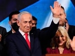 Israeli Prime Minister Benjamin Netanyahu, accompanied by his wife, Sara, waves to supporters at Likud party headquarters in Jerusalem after the release of the first exit poll results.