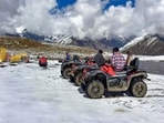 Tourists sit on all-terrain vehicles (ATVs) parked on snow-covered ground following fresh snowfall at Rohtang Pass, in Kullu district, Himachal Pradesh, Friday. (PTI File) Tourists sit on all-terrain vehicles (ATVs) parked on snow-covered ground following fresh snowfall at Rohtang Pass, in Kullu district, Himachal Pradesh, Friday. (PTI File)