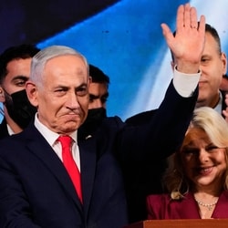 Israeli Prime Minister Benjamin Netanyahu, accompanied by his wife, Sara, waves to supporters at Likud party headquarters in Jerusalem after the release of the first exit poll results.