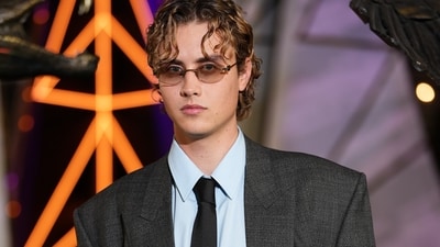 Joseph Zada wore a look from the Gucci Spring Summer 2027 Ready-to-Wear collection, styled by Jason Bolden. The outfit features an oversized grey tweed blazer styled with a pastel blue shirt, black tie, dress shoes, and vintage-style glasses.&nbsp; (AP Photo/Scott A Garfitt)