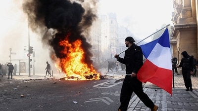A protester holds a French flag next to burning objects amid clashes in a street near the Place de Republique during a day of demonstrations against the cost of living and rising fuel prices in Paris. (REUTERS)