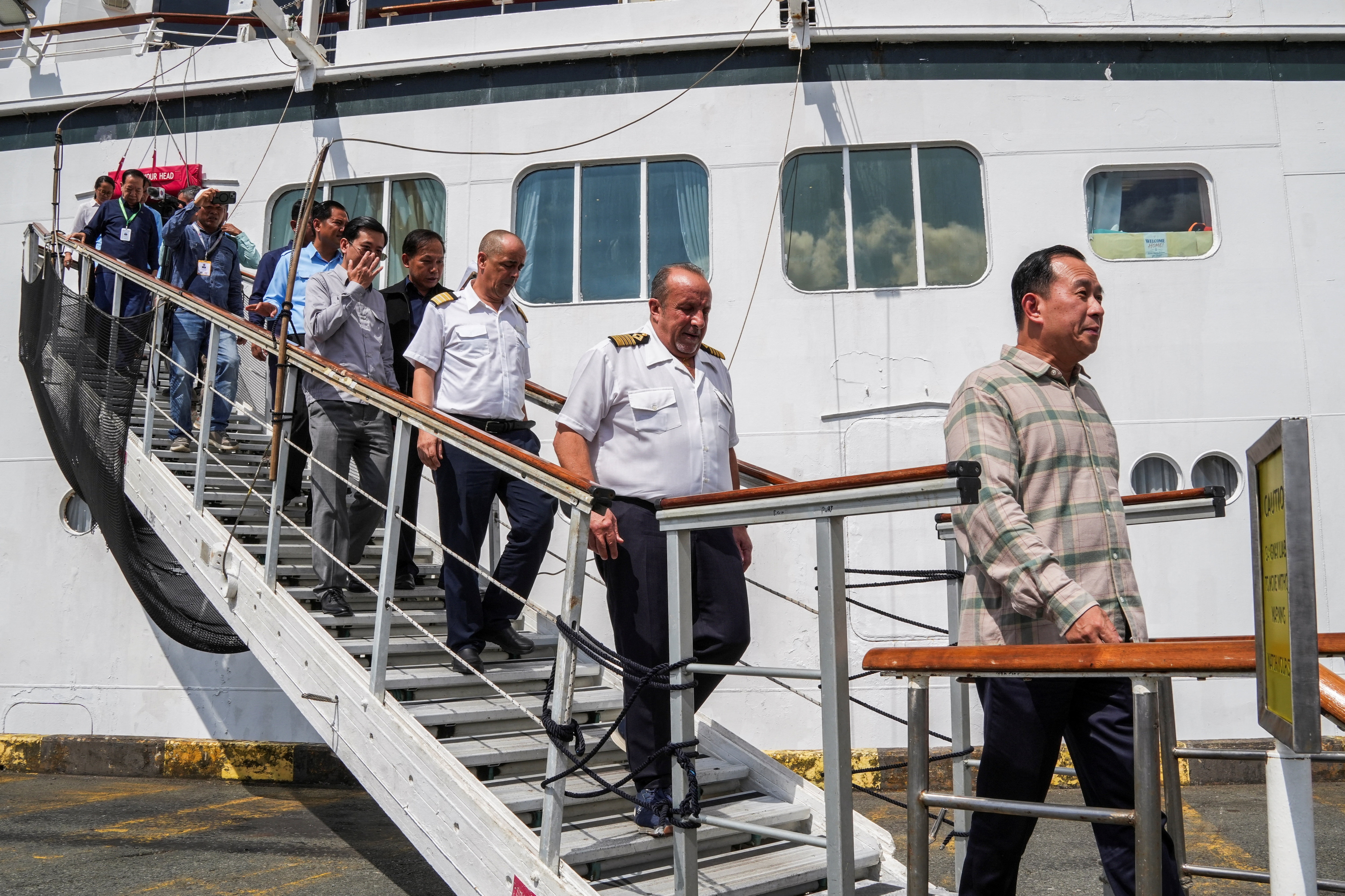 Captain Emanuele Giudice of the Villa Vie Odyssey cruise ship and Cambodia's Minister of Tourism Huot Hak disembark the vessel, which is docked at Sihanoukville Autonomous Port after permanent residents living aboard the vessel were forced to disembark in Cambodia. (REUTERS)