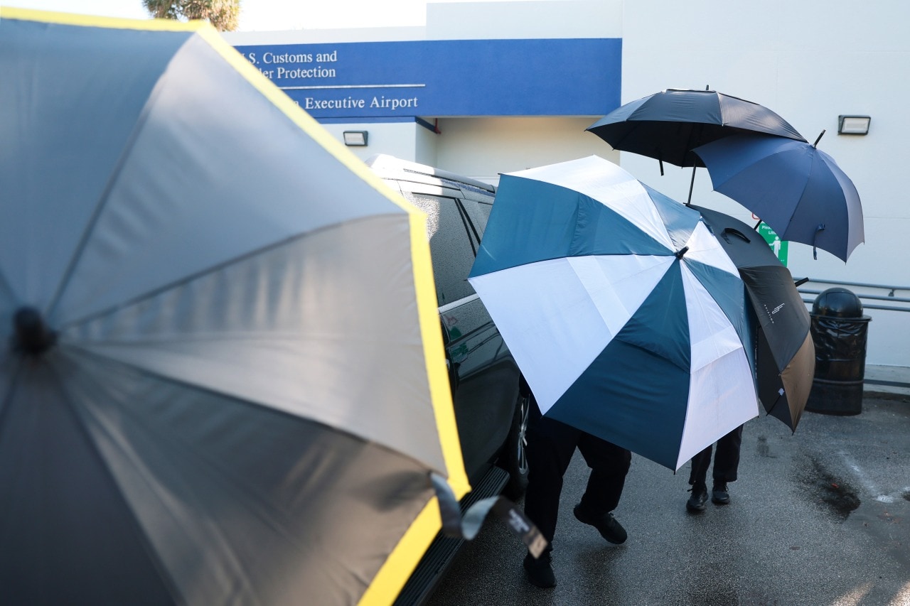 Officers created a shield of umbrellas as they escorted Bolsonaro and his family from the plane to a vehicle in Miami. Officers created a shield of umbrellas as they escorted Bolsonaro and his family from the plane to a vehicle in Miami.