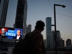 Israel election results highlights: A pedestrian passes a campaign billboard featuring Israeli Prime Minister Benjamin Netanyahu, left, and his main rival, opposition candidate Gadi Eisenkot, with a message in Hebrew that reads "The race is tight".