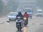 Commuters make their way through a drizzle and thick smog in Gurugram on Thursday. (Parveen Kumar/HT Photo)