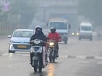 Commuters make their way through a drizzle and thick smog in Gurugram on Thursday. 