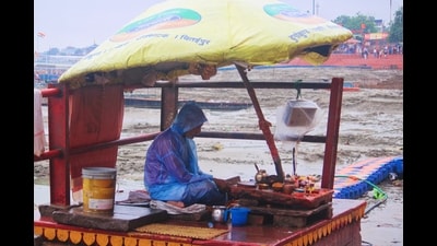 A local vendor keeps himself protected from the rain on Friday in Varanasi (Rajesh Kumar/HT)