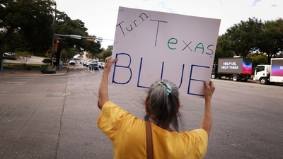 A woman holds a 'Turn Texas Blue' sign during early voting ahead of the November 3 US midterm elections, in Austin. (Reuters Photo)